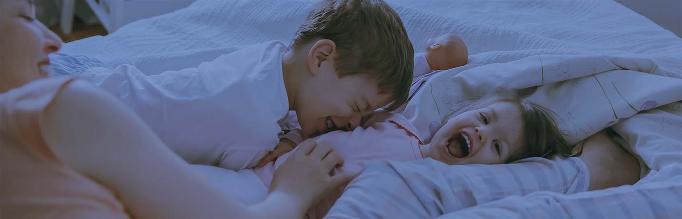 Mom playing with children on bed